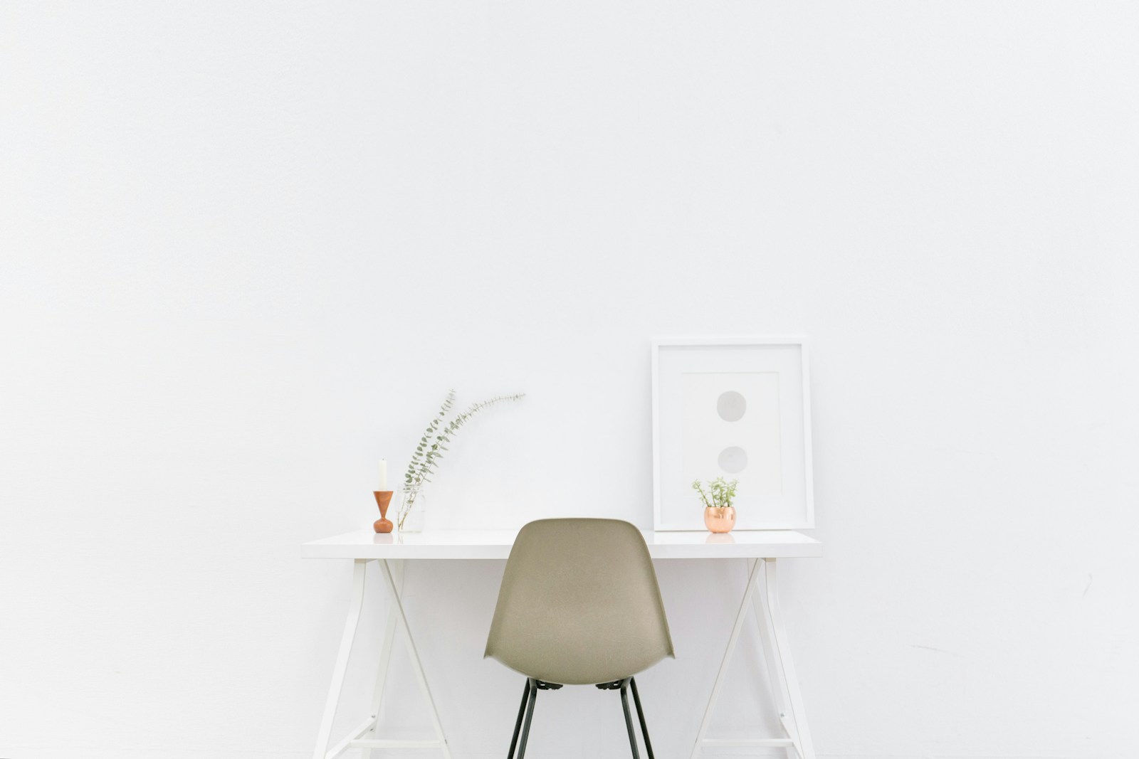 A minimalist white desk and chair in a light-filled home workspace